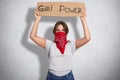 Photo of young cute feminist dressed in white casul t shir, holds sign says Girl power, demands women are equal with men, poses ag Royalty Free Stock Photo