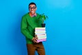 Photo of young cute smiling academic nerd student man wear funky spectacles hold stack books with decorative plant Royalty Free Stock Photo