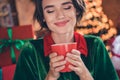 Photo of young dreamy charming positive santa helper woman hold mug rest coffee xmas inside house home