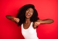 Photo of young excited african girl happy positive smile have fun enjoy music dance isolated over red color background Royalty Free Stock Photo