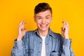 Photo of young excited man crossed fingers wait wish luck pleading isolated over yellow color background