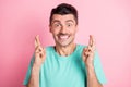 Photo of young excited man happy positive smile crossed fingers expect wish luck isolated over pink color background