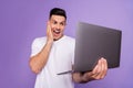 Photo of young excited man happy positive smile surprised look laptop news information isolated over purple color