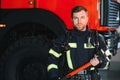 Photo of young fireman with sledgehammer in hands near fire engine Royalty Free Stock Photo