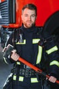 Photo of young fireman with sledgehammer in hands near fire engine Royalty Free Stock Photo