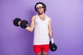 Photo of young funky funny serious man with hair and glasses hold dumbbells exercise isolated on purple color background Royalty Free Stock Photo