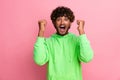 Photo of young funny indian guy curly hair model in green sweatshirt raised fists up football team fan isolated on pink