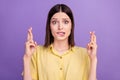 Photo of young girl bite lips teeth fear crossed fingers pleading wish luck isolated over violet color background