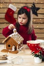 Young girl decorating gingerbread house