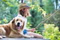 Young girl fishing while sitting with dog on pier Royalty Free Stock Photo