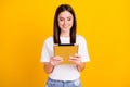 Photo of young girl happy positive smile look read browse tablet isolated over yellow color background