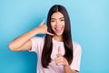 Photo of young girl happy positive smile show fingers call sign phone you isolated over blue color background Royalty Free Stock Photo