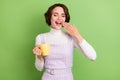 Photo of young girl happy positive smile sleepy morning yawn drink coffee isolated over green color background Royalty Free Stock Photo