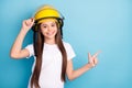 Photo of young girl happy positive smile wear helmet point finger empt space ad promo suggest isolated over blue color