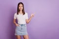 Photo of young girl point finger empty space promo recommend advise decision isolated on violet color background