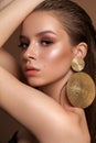 A photo of the young girl with professional make-up, perfect skin, round gold earrings in fashion pose. Royalty Free Stock Photo