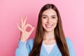 Photo of young good mood positive girl in blue cardigan showing okey gesture smiling on camera isolated on pink color Royalty Free Stock Photo