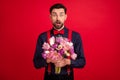 Photo of young handsome amazed surprised man hold bouquet receive birthday present isolated on red color background