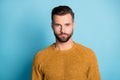 Photo of young handsome attractive serious man look camera wear yellow orange sweater isolated on blue color background Royalty Free Stock Photo