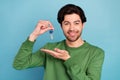 Photo of young handsome cheerful male hold key new home relocation wear green sweater isolated on blue color background