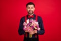 Photo of young happy cheerful handsome gentleman hold bouquet celebrate woman day isolated on red color background Royalty Free Stock Photo