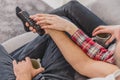 Photo of young happy happy couple sitting on a couch indoors and watching TV. Looking sideways The wife holds a cup in