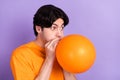 Photo of young happy funky positive man hold hands balloon inflate blow air isolated on violet color background