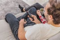 Photo of young happy happy couple sitting on a couch indoors and watching TV. Looking sideways The wife holds a cup in Royalty Free Stock Photo