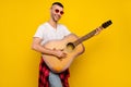 Photo of young happy man wear plaid shirt tied on waist guitar player music isolated on yellow color background Royalty Free Stock Photo