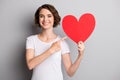 Photo of young happy smile girl point index finger hold big heart valentine day advertise offer isolated over grey color Royalty Free Stock Photo