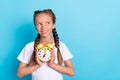 Photo of young little girl happy positive smile dream think look empty space hold timer watch isolated over blue color