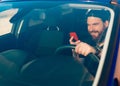 Photo of young man with beard driving car and using phone Royalty Free Stock Photo