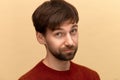 Is it. Photo of young man with beard wearing sweater, looking at camera with question, posing against yellow background