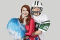 Portrait of young man in football uniform hugging cheerleader over gray background Royalty Free Stock Photo