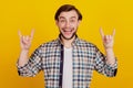 Photo of young man grimacing fooling show fingers rock sign horns isolated over yellow color background