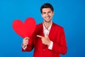 Photo of young man happy positive smile point finger heart figure romantic advice choice advert  over blue color Royalty Free Stock Photo