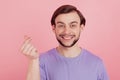 Photo of young man happy positive smile show finger money cash sign isolated over pink color background