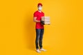 Photo of young man hold three paper boxes wear mask red t-shirt headwear jeans sneakers isolated yellow color background Royalty Free Stock Photo