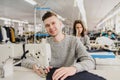 Photo of a young man and other seamstresses sewing with sewing machine in a factory