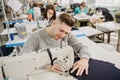 photo of a young man and other seamstresses sewing with sewing machine in a factory