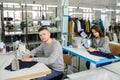 photo of a young man and other seamstresses sewing with sewing machine in a factory
