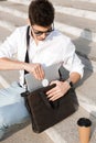 Photo of young man 30s wearing sunglasses, putting laptop into h Royalty Free Stock Photo