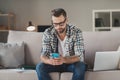 Photo of young man serious sit couch home look read browse internet cellphone wear casual outfit freelancer Royalty Free Stock Photo