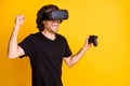 Photo of young man virtual reality hold joystick open mouth raise arm fist wear vr helmet t-shirt isolated yellow color