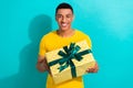 Photo of young man wear yellow t-shirt hold package giftbox present surprise birthday holiday greeting isolated on blue