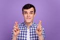 Photo of young man worried nervous crossed fingers wish luck hope isolated over violet color background