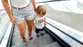 Photo of young mother holding her little son by hand while riding on the escalator at shopping mall Royalty Free Stock Photo