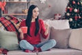 Photo of young pretty girl sit sofa hold cup cell phone open mouth wear red sweater jeans socks in decorated living room Royalty Free Stock Photo
