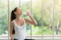 Photo of young pretty woman in sportswear drinking water and sitting doing yoga exercises at home Royalty Free Stock Photo