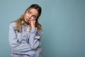 Photo of young sad upset sorrowful beautiful blonde woman with sincere emotions wearing denim blue jacket isolated over